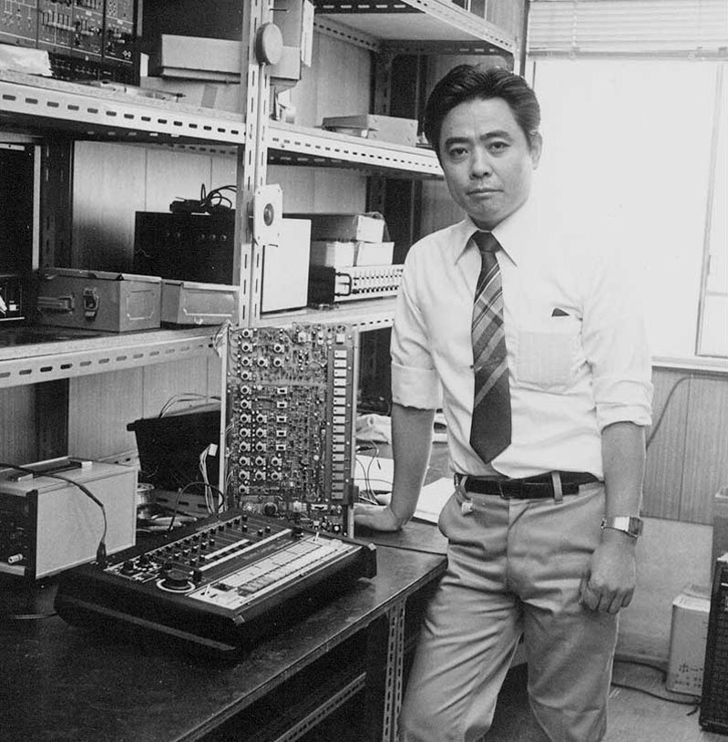 Tadao Kikumoto beside an early TR-808 in an engineering workspace