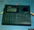 BOSS DR-550 photographed from above on a blue-green surface, showing its LCD, dial and pads.
