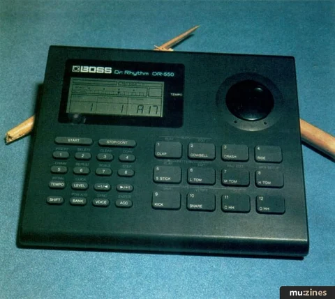 BOSS DR-550 photographed from above on a blue-green surface, showing its LCD, dial and pads.