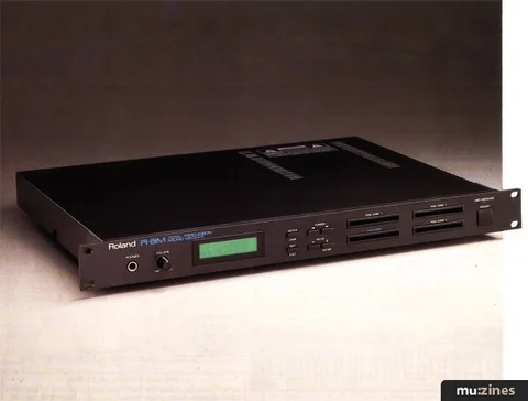 Angled photograph of the black Roland R-8M rack unit with its green display and front-panel controls.