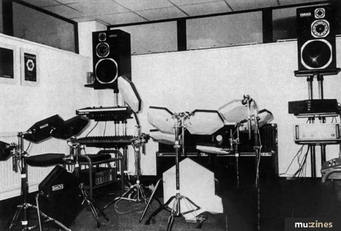Black-and-white studio photograph of an electronic drum kit between monitor speakers.