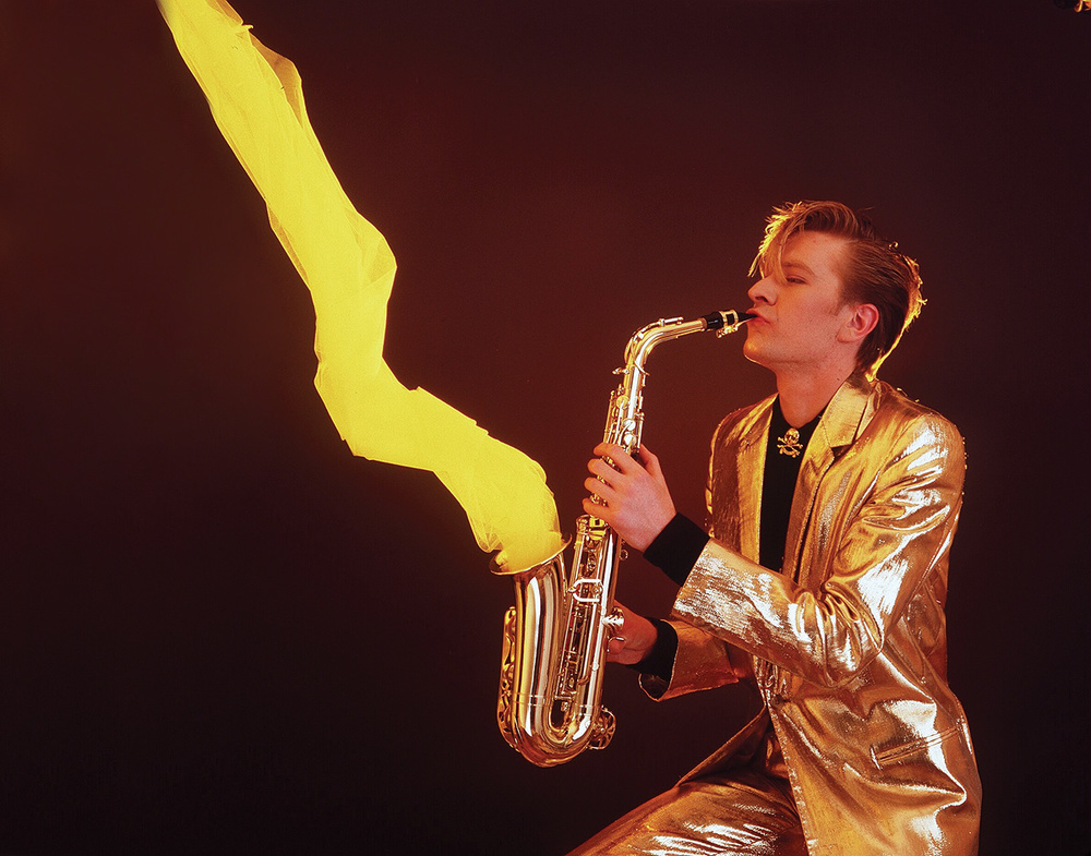 Martin Fry of ABC performing with saxophone in a gold lamé suit.